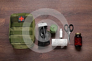 Flat lay composition with military first aid kit and tourniquet on wooden table