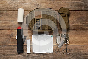 Flat lay composition with military first aid kit on wooden table