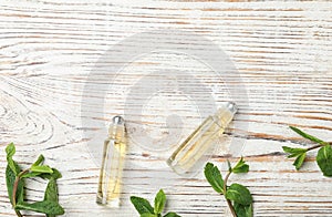 Flat lay composition with mint essential oil on white wooden background