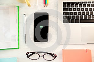 Flat lay composition with mobile phone and wireless charger on wooden table. Modern workplace accessory