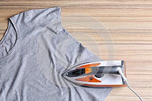 Flat lay composition with modern electric iron and t-shirt on wooden table