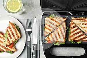 Flat lay composition with modern sandwich maker and breakfast served on grey table