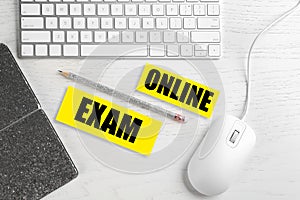 Flat lay composition with mouse, keyboard and phrase ONLINE EXAM on wooden table