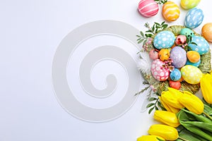 Flat lay composition with nest, Easter eggs, feathers and flowers on color background