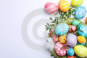 Flat lay composition with nest, Easter eggs, feathers and flowers on color background