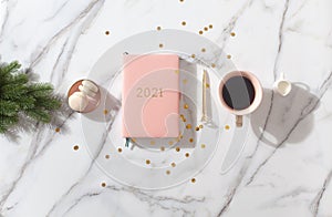 Flat lay composition with New Year`s decoration, coral colored 2021 diary book and coffee cup and Macaron cookie