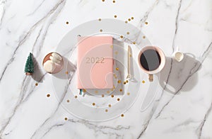 Flat lay composition with New Year's decoration, coral colored 2022 diary book and coffee cup and Macaron cookie