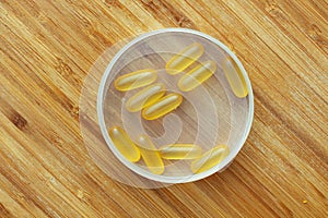 Flat lay composition of Omega 3 gel capsules on the wooden table