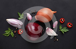 Flat lay composition with onions and spices on black background
