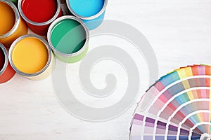 Flat lay composition with paint cans and color palette on wooden background.