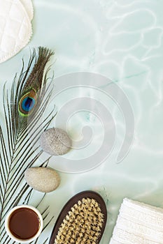 Flat lay composition with peacock feather, massage stones, oil, towel and body brush