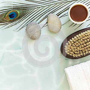 Flat lay composition with peacock feather, massage stones, oil, towel and body brush