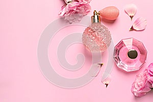 Flat lay composition with perfume bottles and flowers on pink background, space for text