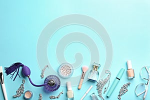 Flat lay composition with perfume bottles, jewelry and cosmetic products on light blue background, space