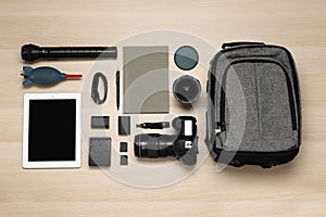 Flat lay composition with photography equipment and backpack on wooden table