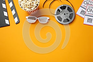 Flat lay composition with popcorn and film reel on orange background, space for text