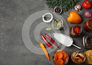 Flat lay composition with products and jars of pickled vegetables on grey table