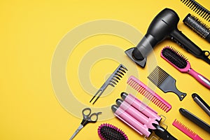 Flat lay composition of professional hairdresser tools on orange background, space for text