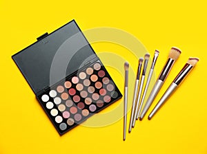 Flat lay composition with professional makeup brushes and eye shadow palette