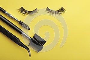 Flat lay composition of professional makeup tools and false eyelashes on color background