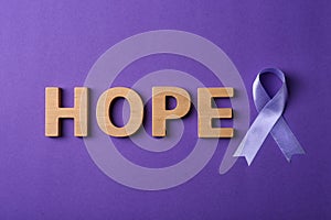 Flat lay composition with purple ribbon and word HOPE on violet background