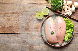 Flat lay composition with raw chicken breasts and ingredients on wooden background.