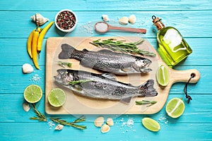 Flat lay composition with raw cutthroat trout fish on blue wooden table