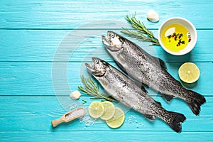 Flat lay composition with raw cutthroat trout fish on blue wooden table, space for text