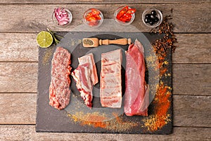 Flat lay composition with raw meat, vegetables and spices on wooden background