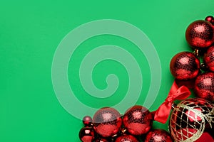 Flat lay composition with red Christmas balls on green background. Space for text