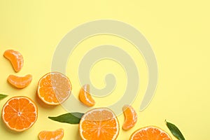 Flat lay composition with ripe tangerines and leaves on light yellow background, space for text. Citrus fruit