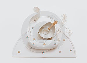 Flat lay composition with set of baby bibs and plate on beige background.