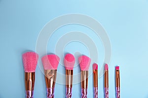 Flat lay composition with set of professional makeup brushes on light blue background