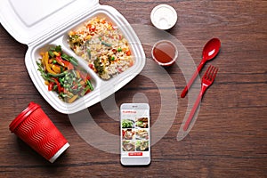 Flat lay composition with smartphone and takeout meal on wooden background. Food delivery