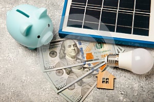 Flat lay composition with solar panel, led lamp and piggy bank on background.