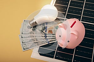 Flat lay composition with solar panel, led lamp and piggy bank on yellow background.