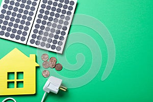 Flat lay composition with solar panels, house model and coins on background. Space for text