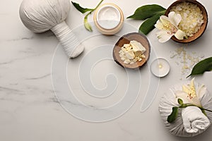 Flat lay composition with spa products and flowers on white marble table. Space for text