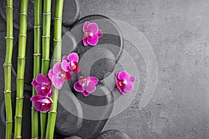 Flat lay composition with spa stones,  and orchid flowers on grey background. Space for text