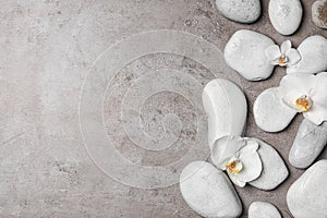 Flat lay composition with spa stones and orchid flowers on grey background