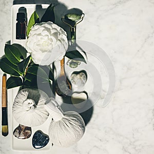 Flat lay composition with spring camelia flower and various beauty care products on white marble table