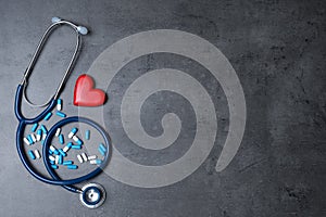 Flat lay composition with stethoscope, heart and pills on grey background, space for text.