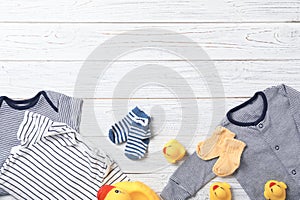 Flat lay composition with stylish baby clothes and toys on wooden background