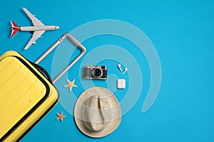 Flat lay composition with suitcase and travel accessories on light blue background, space for text. Summer vacation