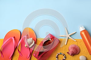 Flat lay composition with sunscreen and beach accessories on light blue background. Space for text