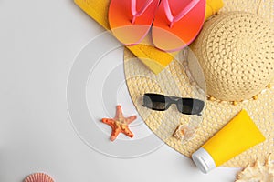 Flat lay composition with sunscreen and beach accessories on white background, space for text