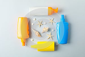 Flat lay composition with sunscreen sprays and starfishes on color background, space for text