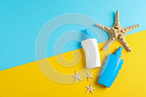 Flat lay composition with sunscreen sprays and starfishes on two tone background, space for text. Summer vacation