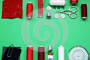 Flat lay composition with thimbles and different sewing tools on green background. Space for text