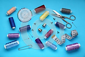 Flat lay composition with thimbles and different sewing tools on light blue background